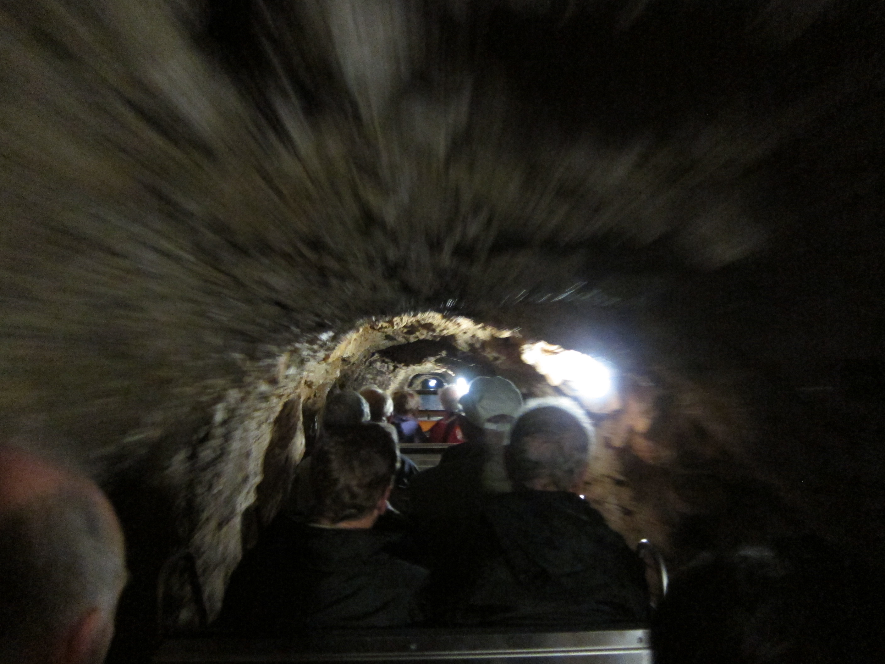 Motion blur of riding an open-topped small train through a cave tunnel.