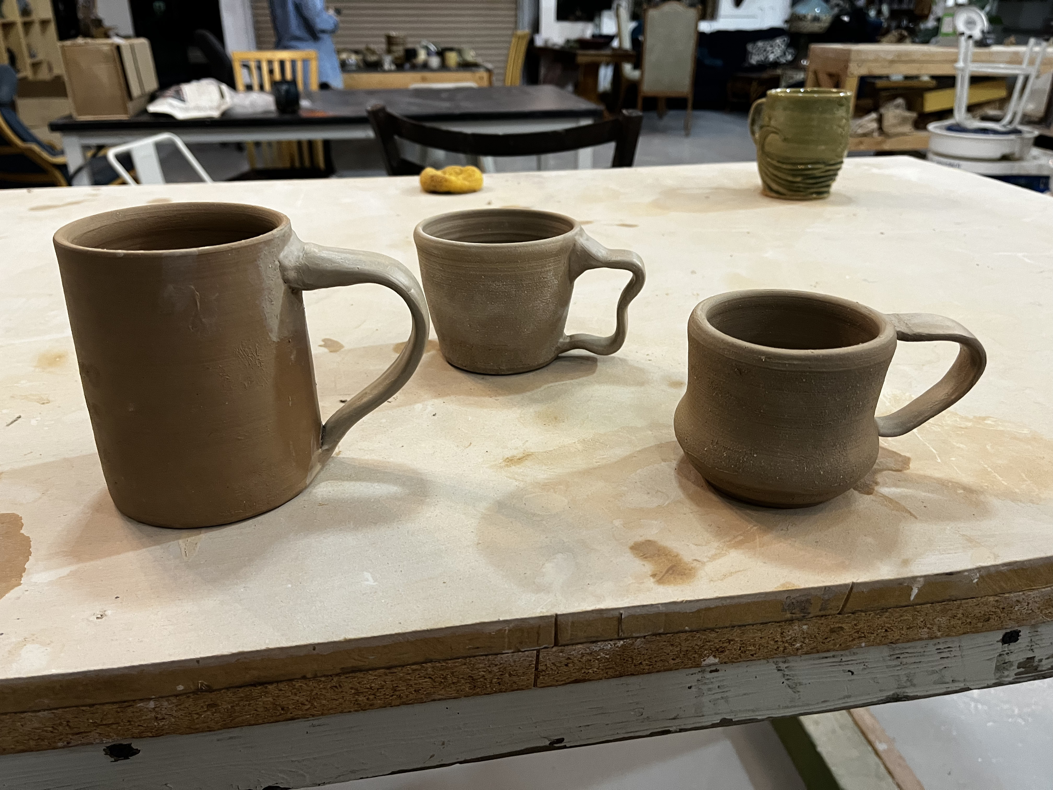 Three mugs with handles. The left-most mug was thrown by the teacher, but I added the handle.