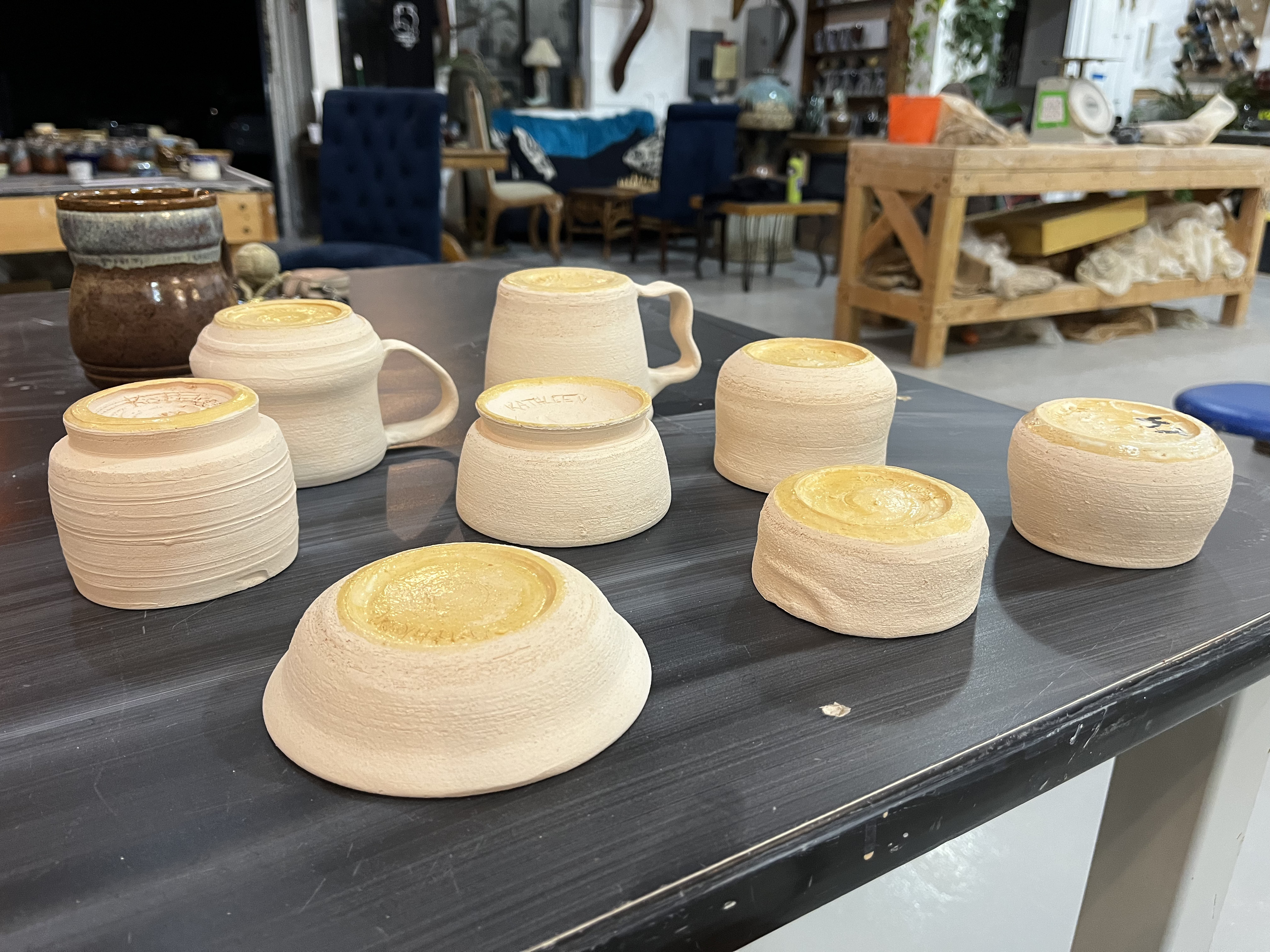 A collection of bisque fired pieces, upside down with wax on their bottoms.