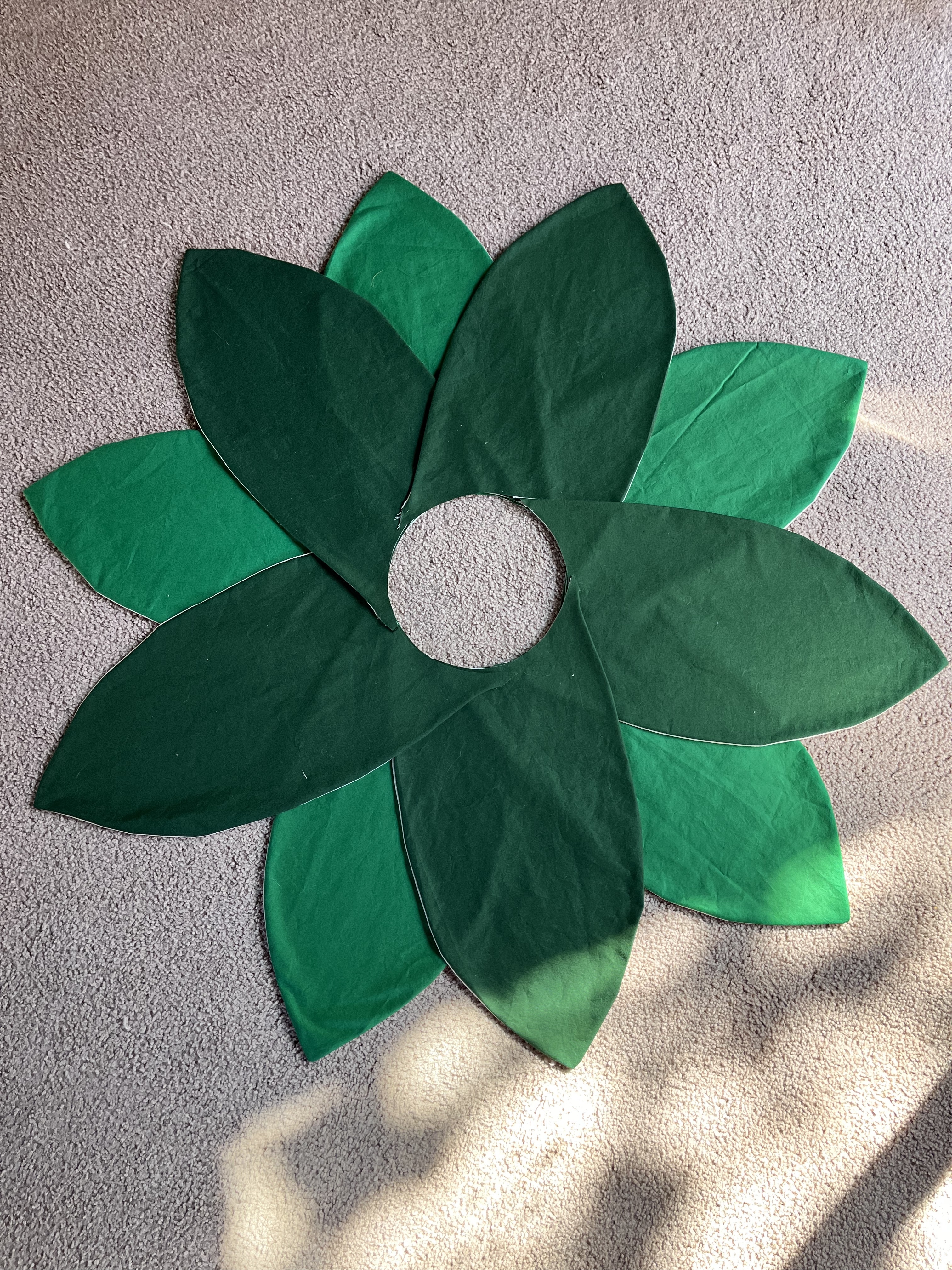 Five dark green petals arranged over 5 lighter green petals sewn together with a neat circular hole in the center