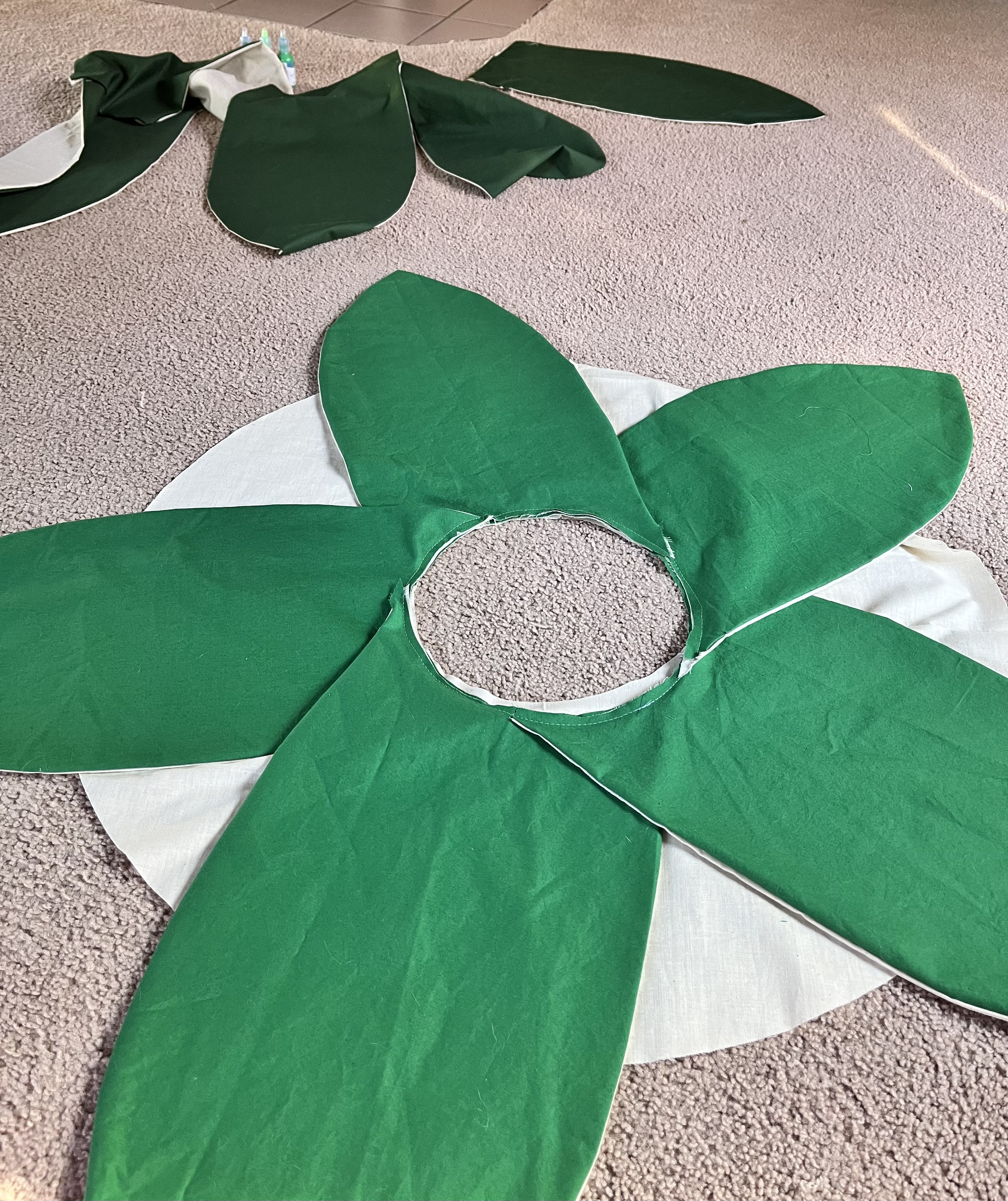 Five lighter green petals arranged in a circle above a light colored fabric circle