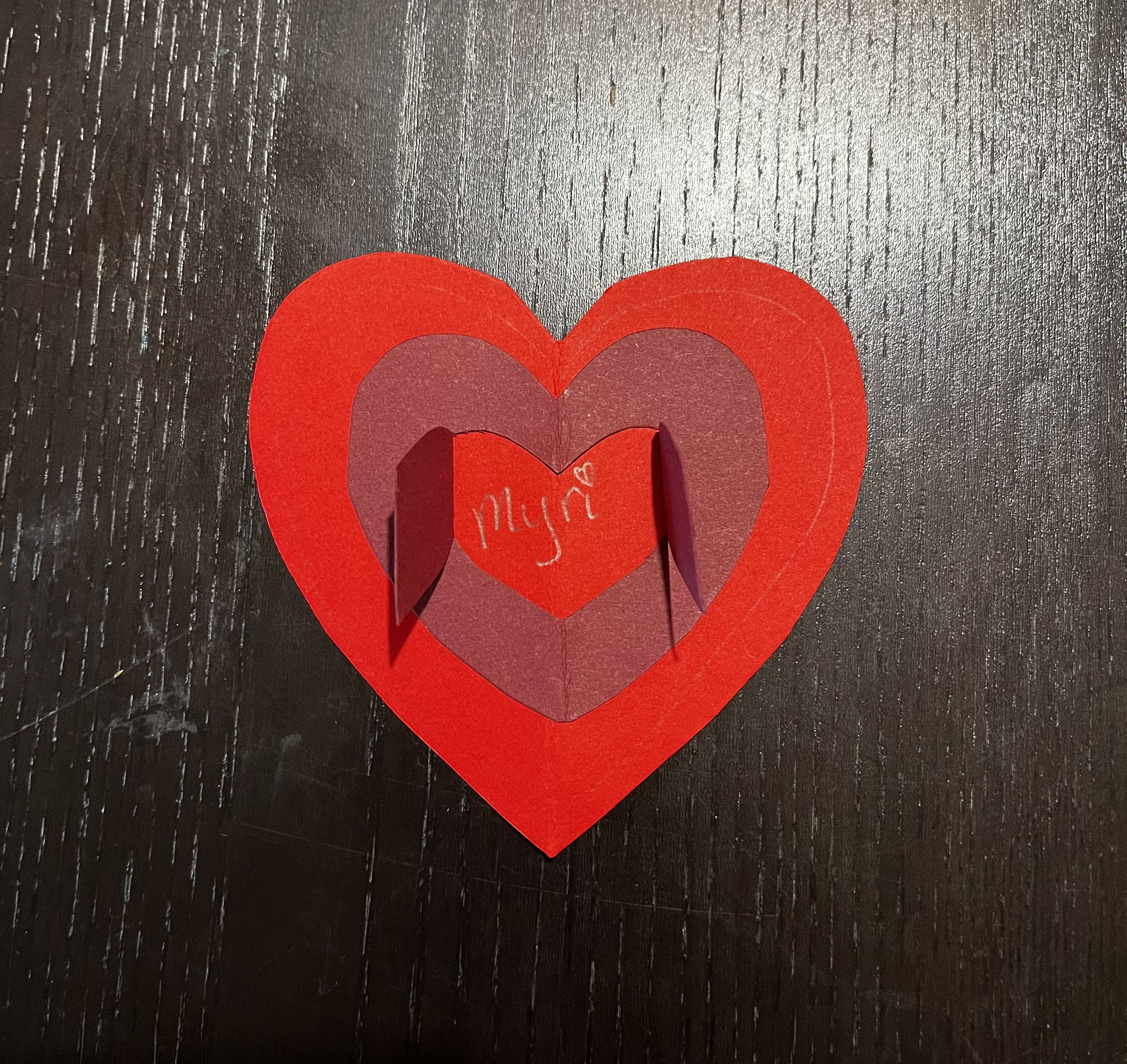 The same two-toned paper heart, but with the doors open revealing the inside message.